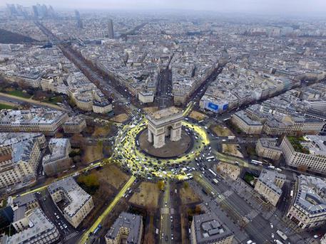 Un gruppo di attivisti di Greenpeace hanno scalato l'Arco di Trionfo a Parigi, con striscioni che chiedono al governo francese e al presidente Francois Hollande di fare di più per la transizione energetica. Altri militanti hanno invaso la piazza sottostante, dipingendo con "eco-pittura gialla" la grande rotonda e le strade che da lì si diramano per disegnare un grande sole e chiedere così "un futuro di energie rinnovabili", 11 dicembre 2015. ANSA/TWITTER/GREENPEACE +++ ANSA PROVIDES ACCESS TO THIS HANDOUT PHOTO TO BE USED SOLELY TO ILLUSTRATE NEWS REPORTING OR COMMENTARY ON THE FACTS OR EVENTS DEPICTED IN THIS IMAGE; NO ARCHIVING; NO LICENSING +++